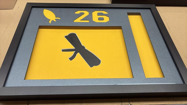 Yellow and grey number 26 sign framed in a charcoal frame