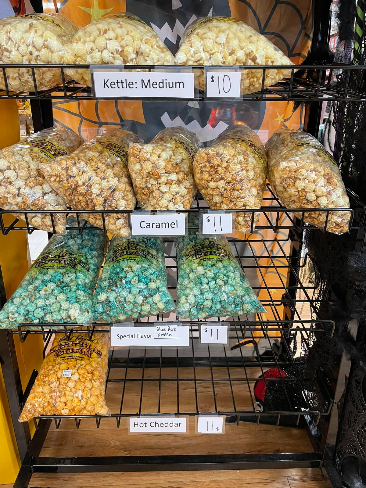 Wire rack of kettle corn bags at Mahaska Drug, labelled by flavor and size