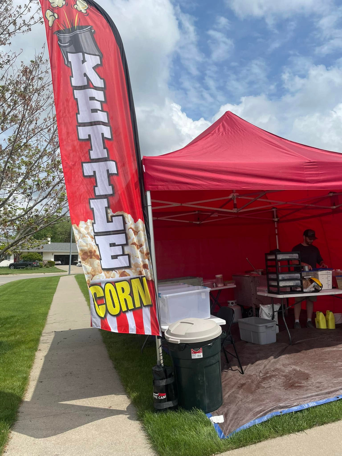 Kettle corn tent and feather flag set up on the lot at an outdoor event