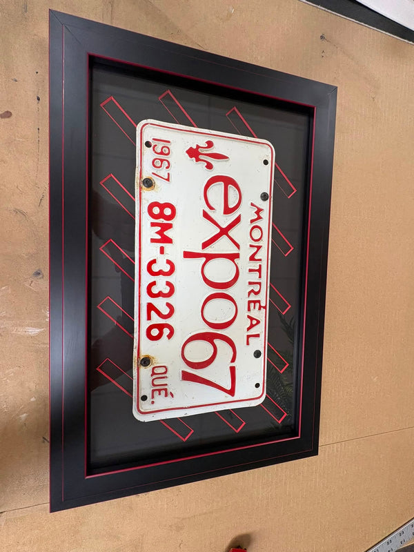 Framed 1967 Expo 67 Montreal license plate on a black mat with a red pinstripe